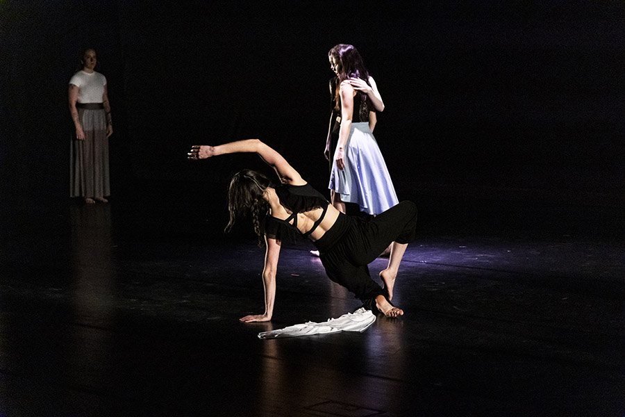 Sheridan College Dance photo portraying four dancers on stage, one with the arm in the air, and two looking on.