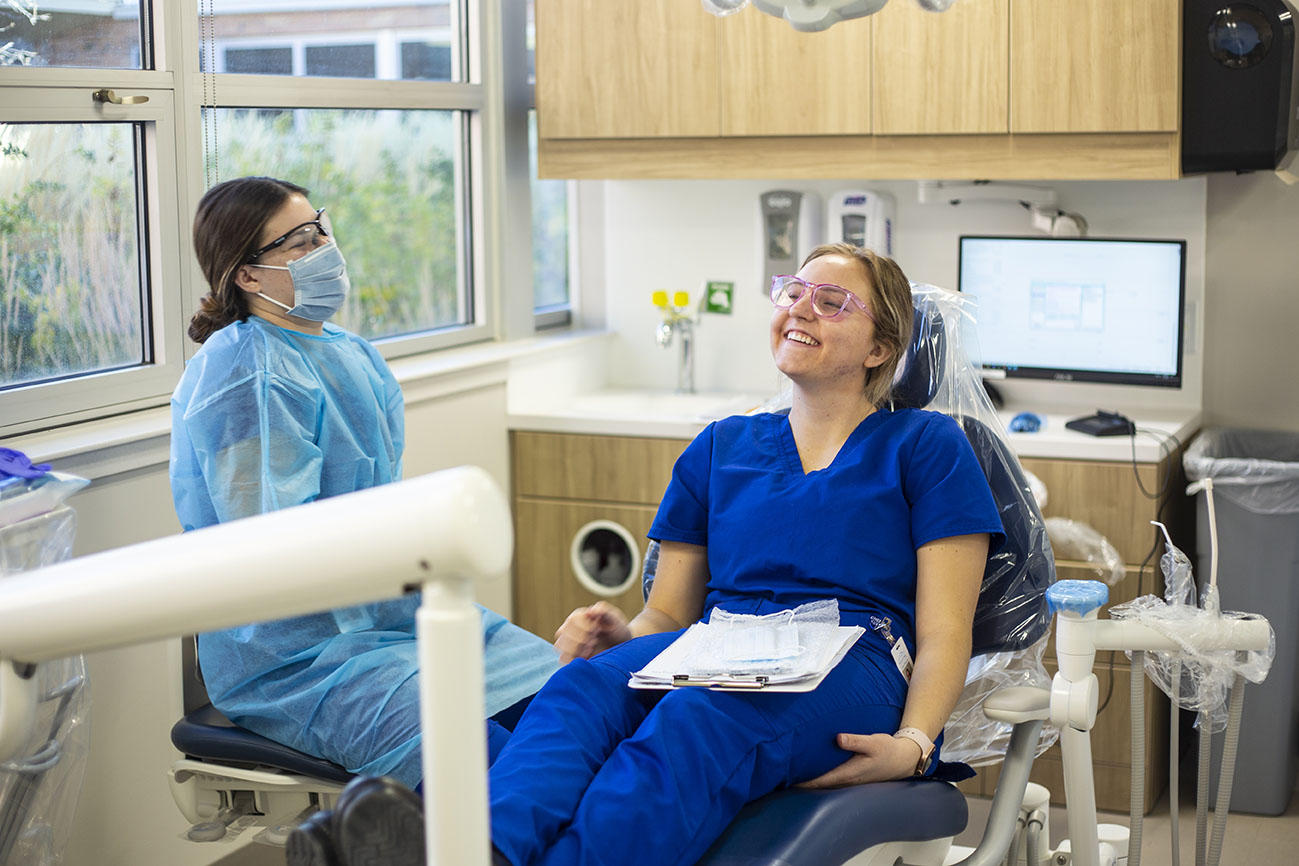 Dental Hygiene Clinic Dental Hygiene students in the clinic, one is in the chair smiling.