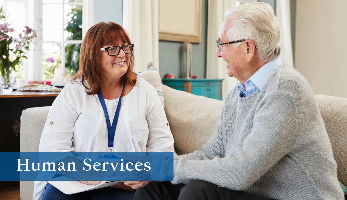 Human Services Photo of two older individuals, one clearly in a supportive role offering guidance to the other.
