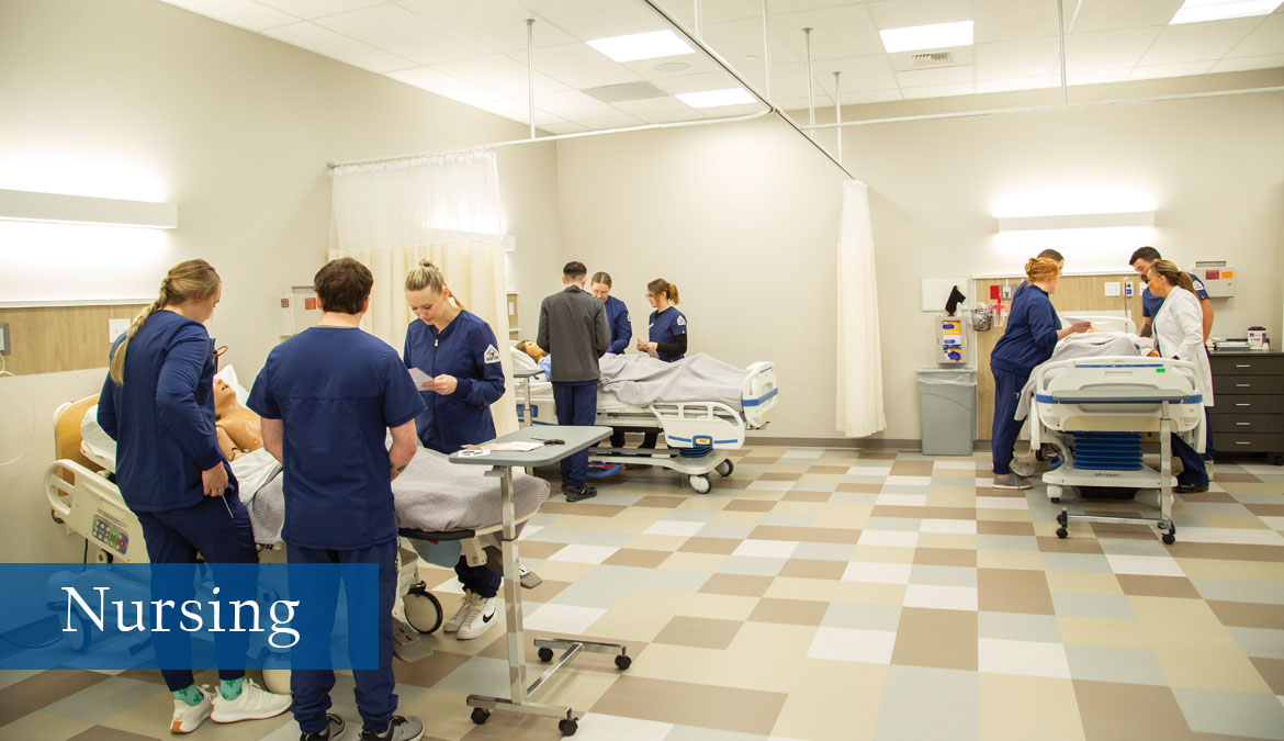 Nursing program at Sheridan College Nursing students in three groups working with manikens during a simulation.