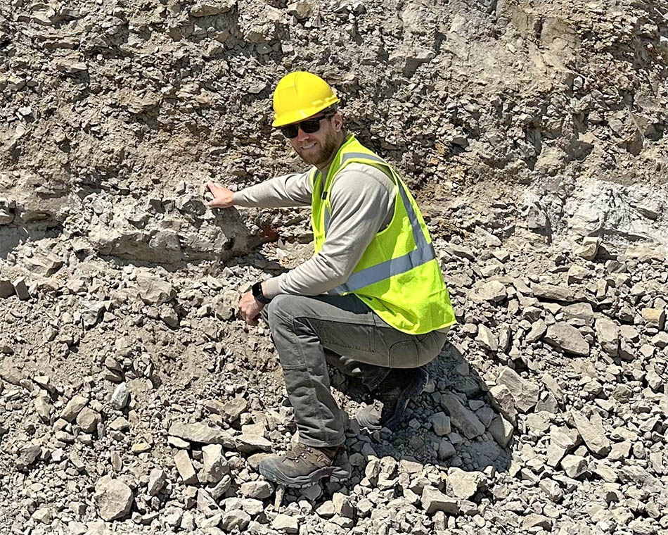 Image of Alex Moyes working with a hard hat and yellow vest likely in a mine site.